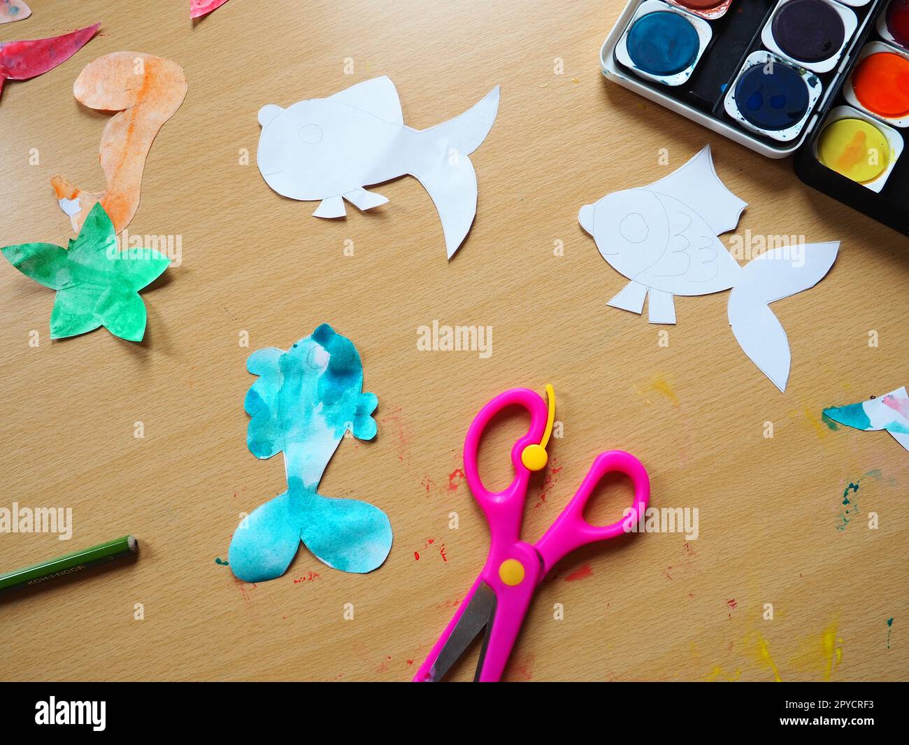 Desktop with drawing tools. A set of watercolor paints, pink scissors ...