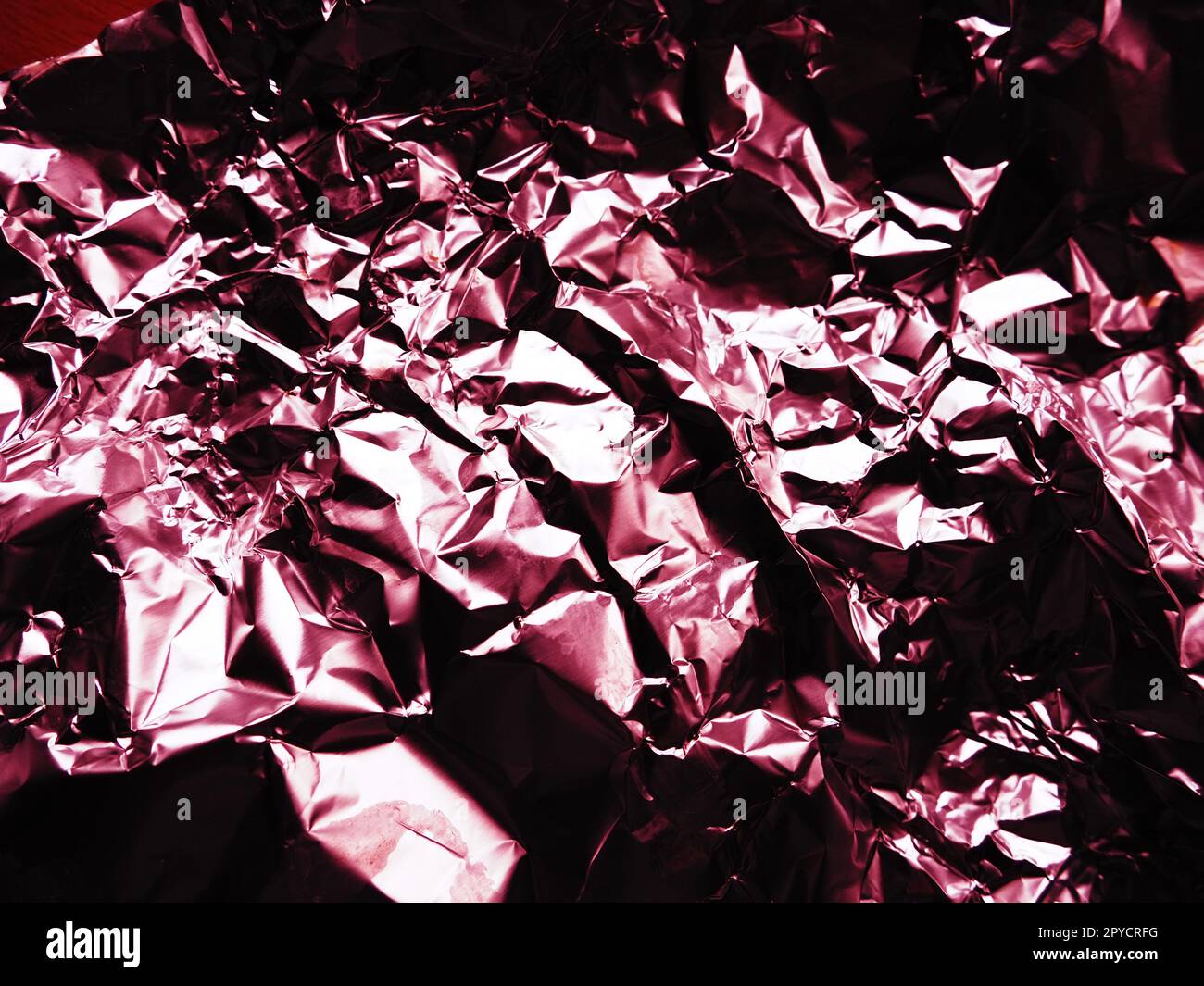 foil close-up. Aluminum silver crumpled foil. Abstract metallic background. Foil for baking food. Background with a red or burgundy tint Stock Photo