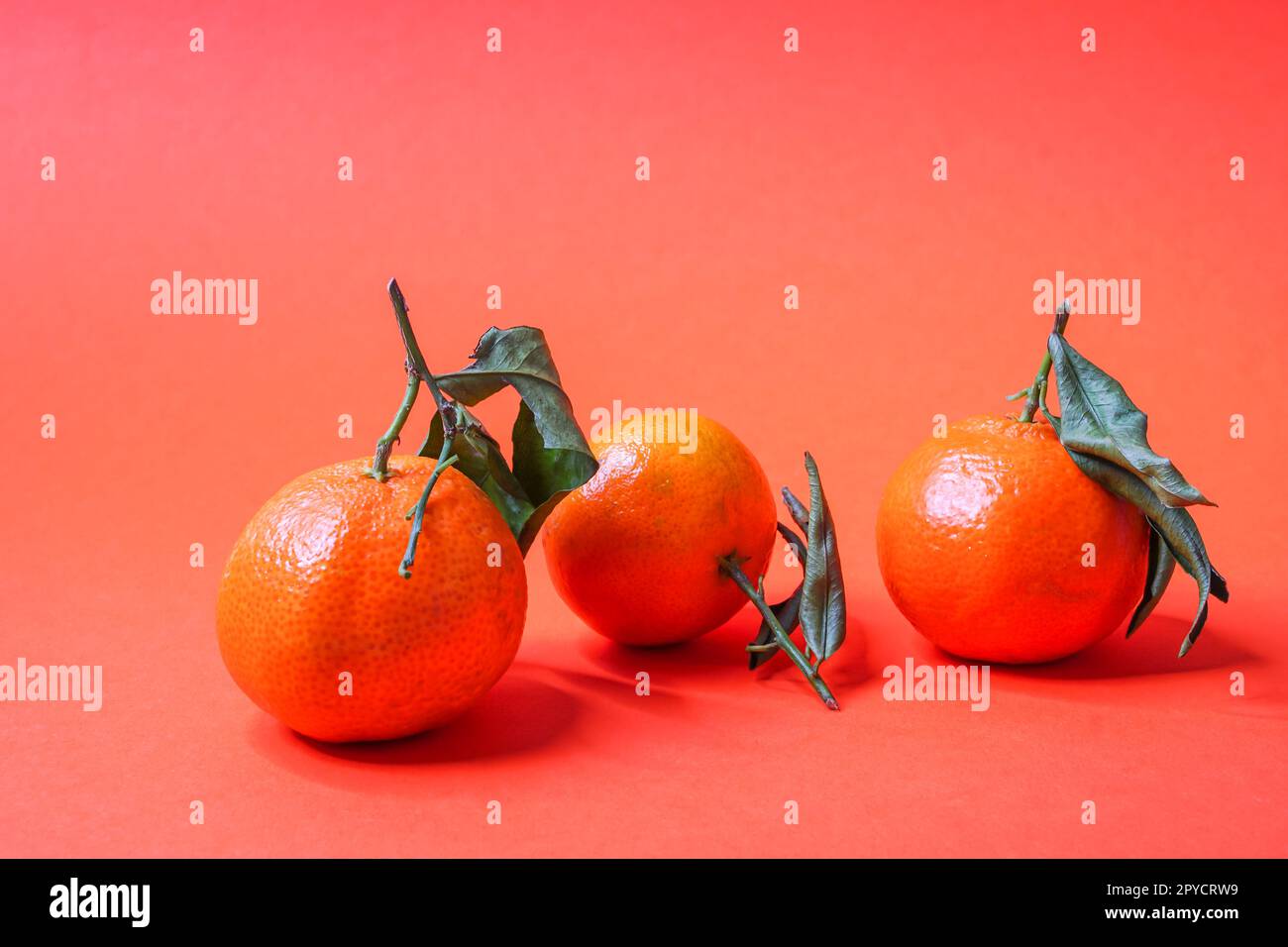 Ripe mandarin fruit (Citrus reticulata) with leaves on an orange background Stock Photo