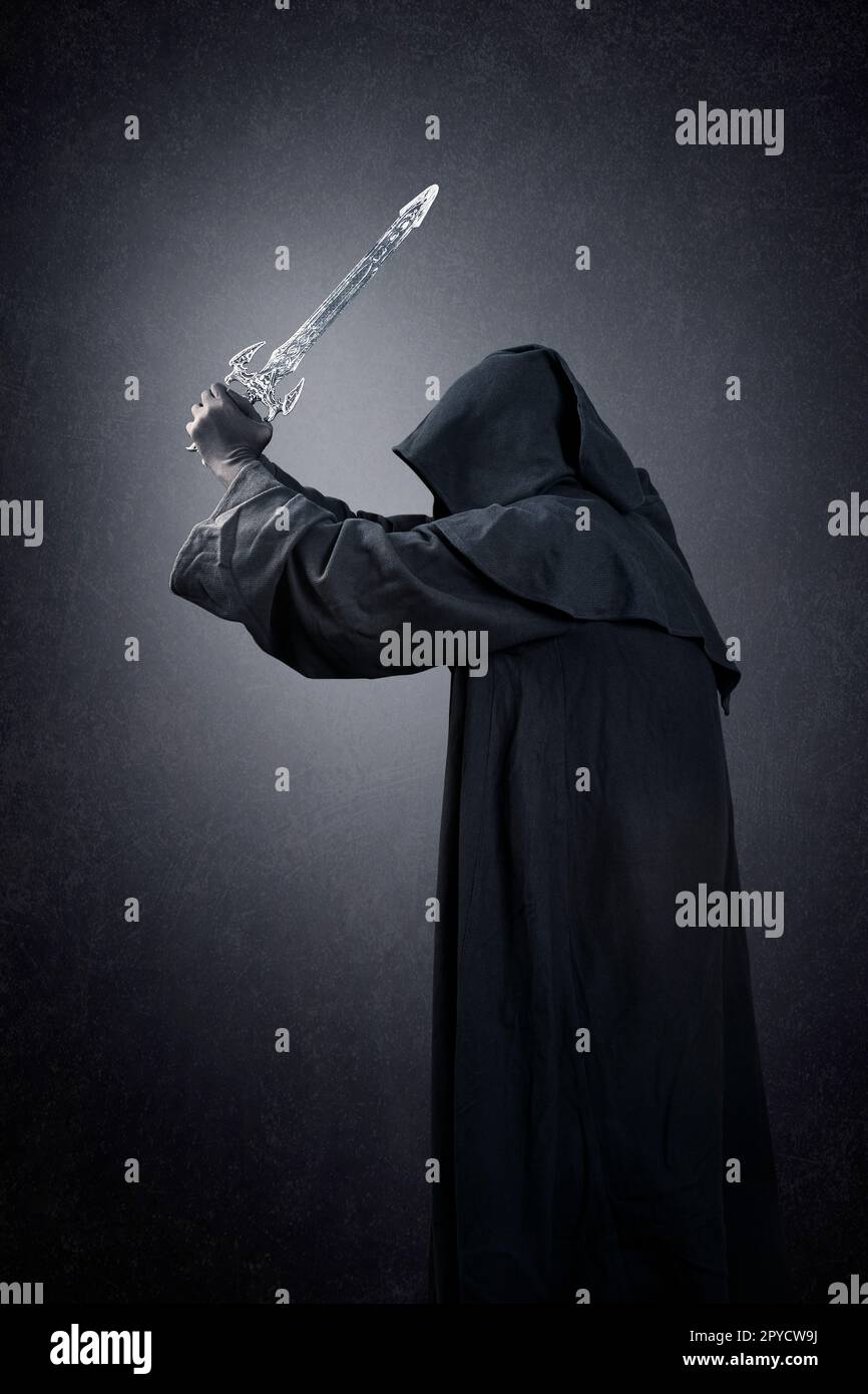 Dark knight with hooded cape and medieval sword over dark misty background Stock Photo