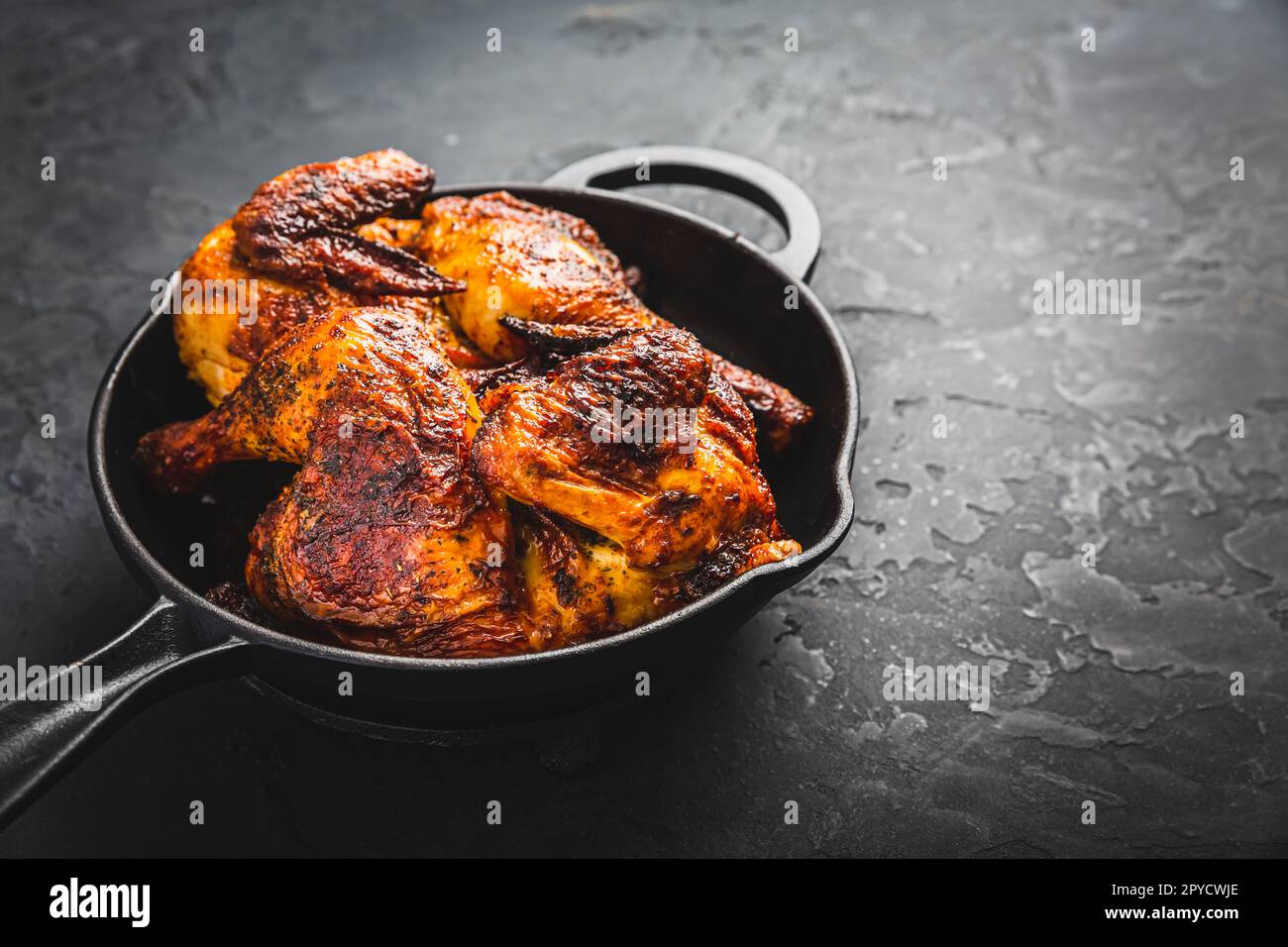 Roasted half chicken in pan on black background Stock Photo
