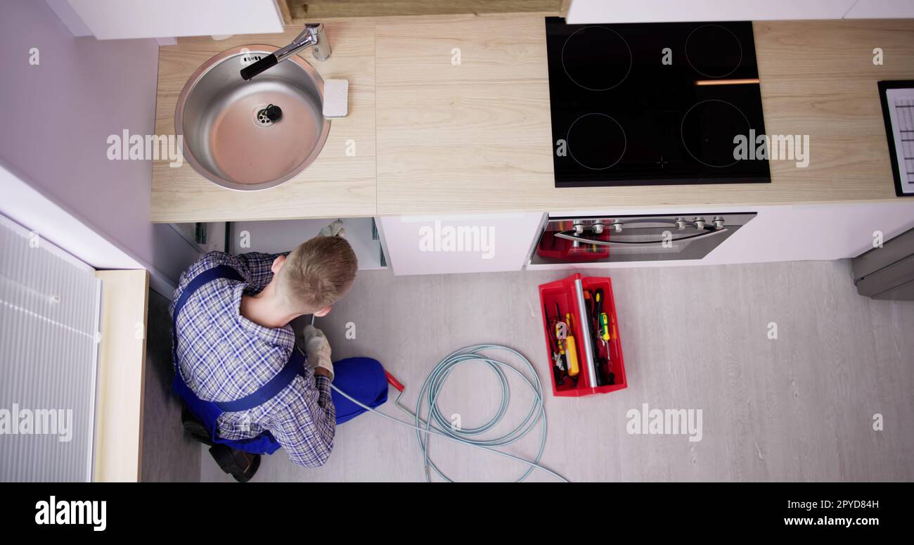 Plumber Drain Cleaning Services In Kitchen Stock Photo