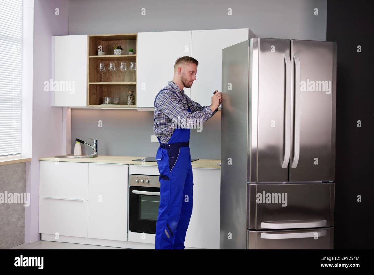 Male Worker Repairing Refrigerator With Screwdriver Stock Photo