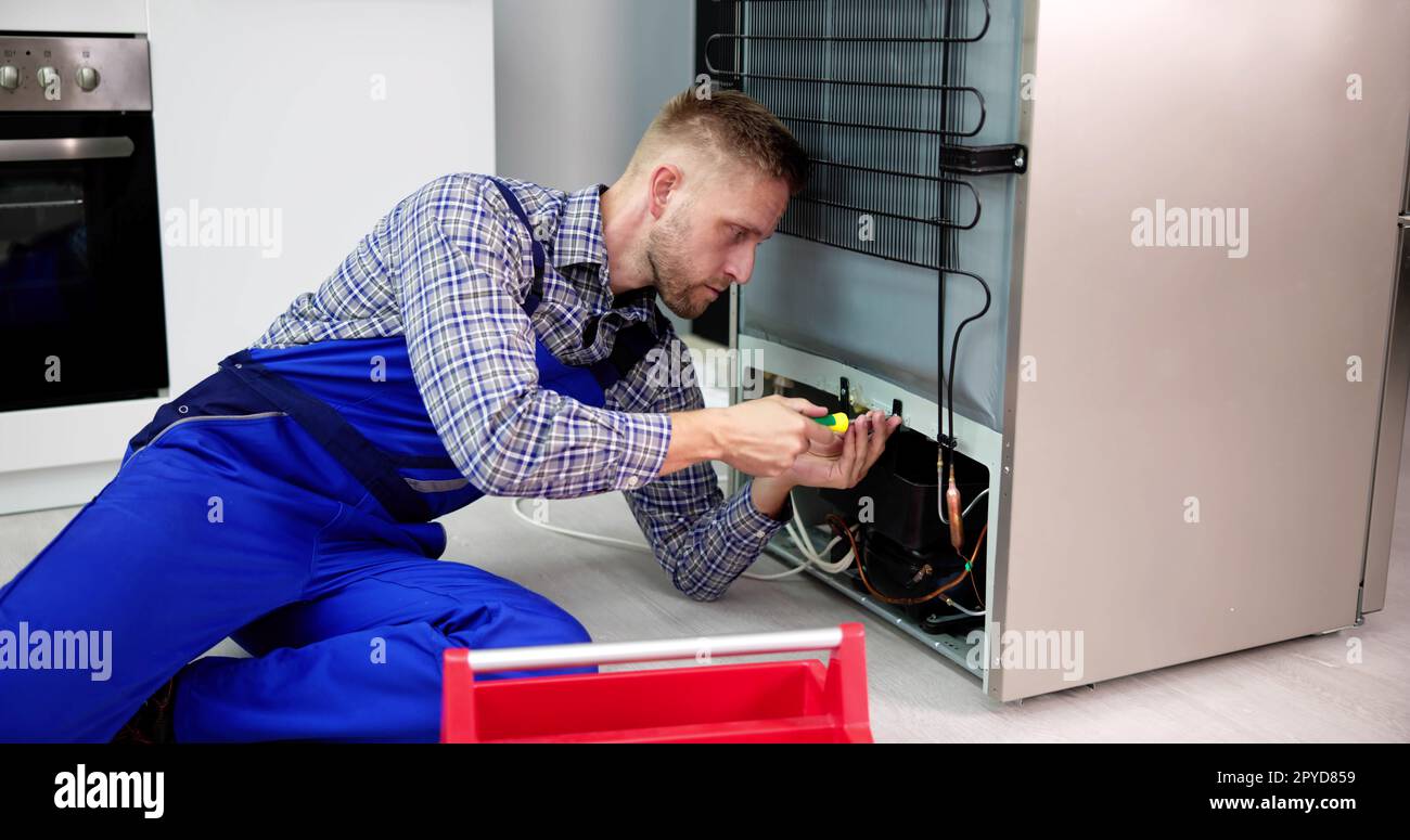 Cropped Image Of Serviceman Working On Fridge With Screwdriver Stock Photo