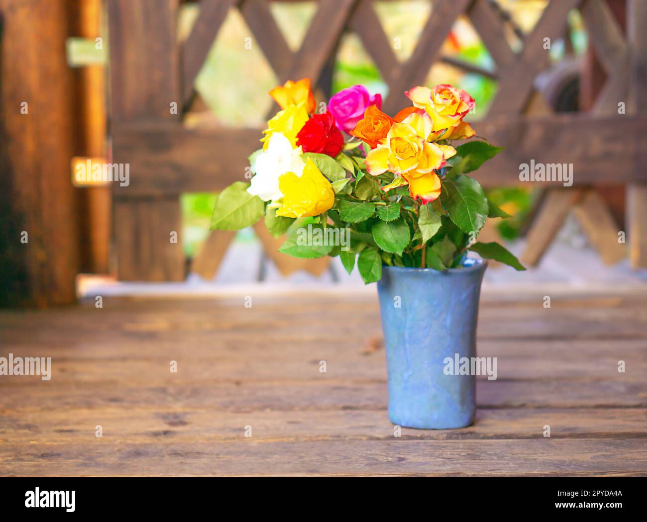 Early spring stil life with a bouquet of colorful roses on the old wooden background. Stock Photo