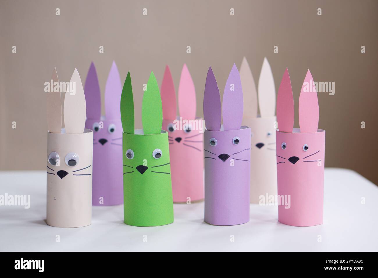 A banner from handmade easter bunny toy gift on a white table background. Many paper easter rabbits made from toilet paper rolls. Happy easter. High quality photo. Stock Photo