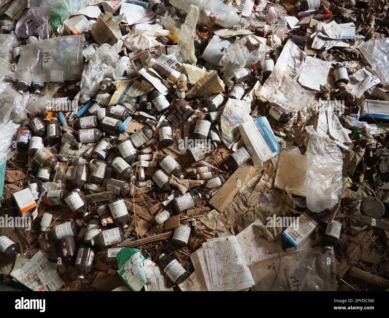 Sremska Mitrovica, Serbia. 07 February 2021, Room with trash in an abandoned house. Packages, paper, plastic items, medicines, bottles, packages, syringes on a wooden floor. Stock Photo