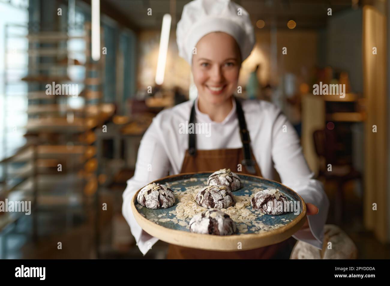Pastry chef presenting freshly baked cookies at bakery kitchen Stock Photo