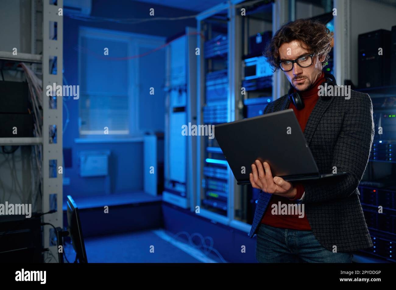 Network engineer using digital tablet in server room during maintenance