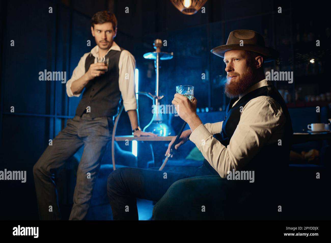 Serious guys smoking hookah while rest in the pub Stock Photo