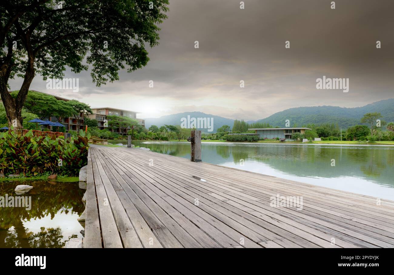 Wooden bridge at the lake in a sustainable hotel near the mountain. Luxury hotel in the forest. Green luxury hotel in the valley. Nature retreat. Lakefront hotel. Travel destinations for retreat mind. Stock Photo