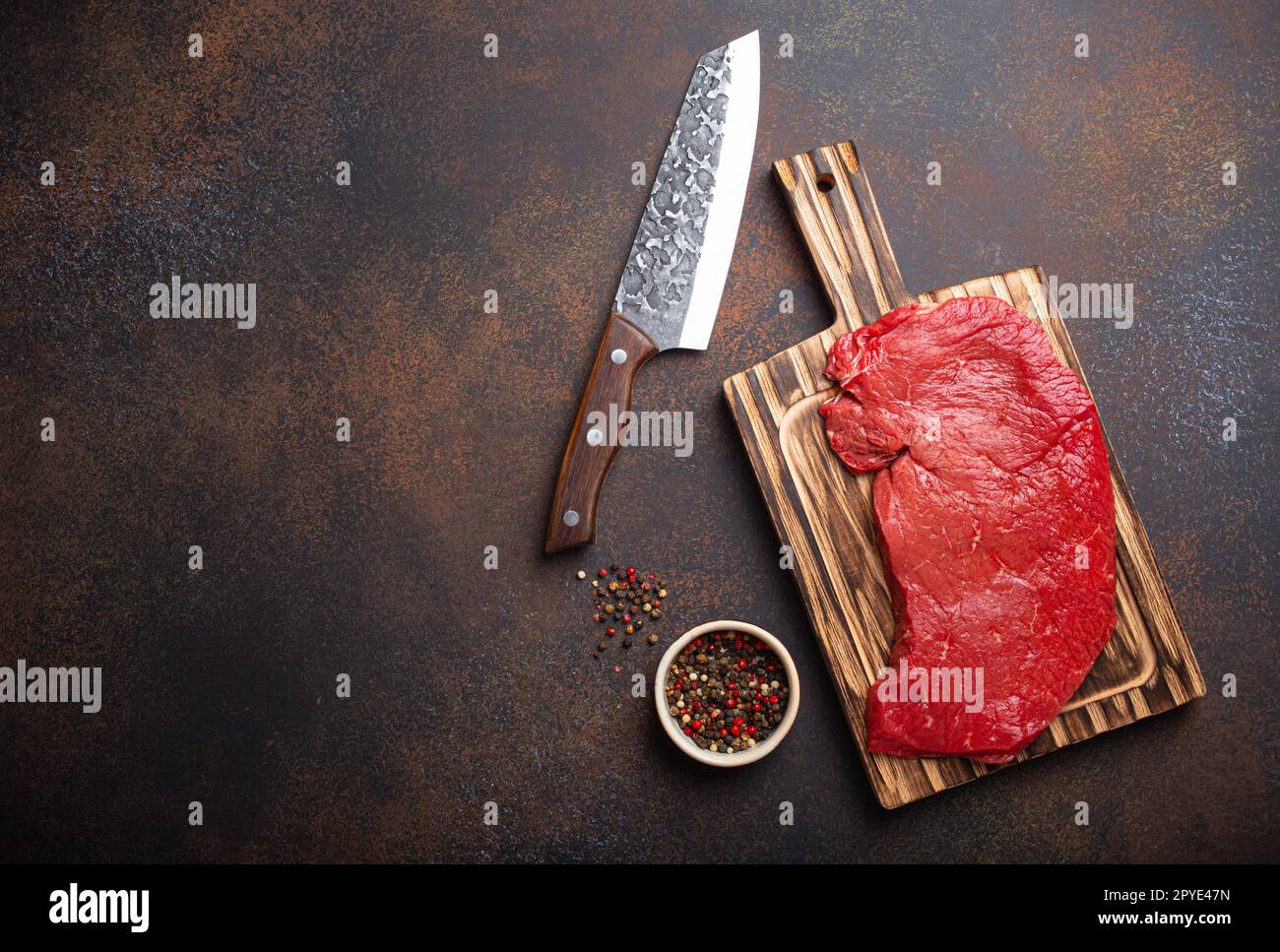 https://c8.alamy.com/comp/2PYE47N/raw-uncooked-top-round-beef-steak-on-wooden-cutting-board-with-big-kitchen-knife-and-pepper-on-dark-brown-rustic-stone-background-top-view-cooking-2PYE47N.jpg