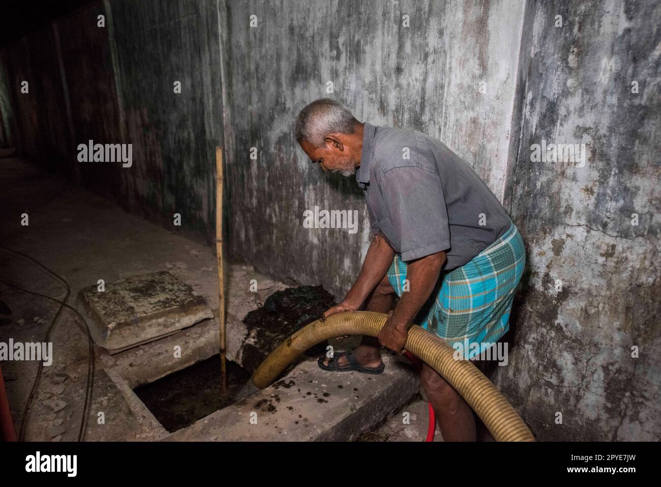 Bangladesh, Khulna. A man empties fecal sludge from a septic tank late at night at a Mosque. March 19, 2017. Editorial use only. Stock Photo