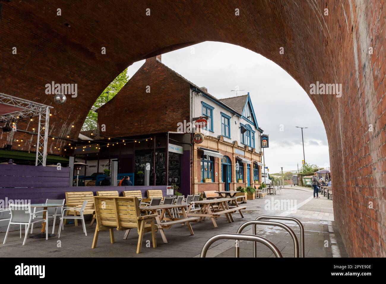 A view of The Tyne bar or pub, in Newcastle upon Tyne, UK, seen through an arch of Glasshouse Bridge in the Ouseburn area of the city. Stock Photo