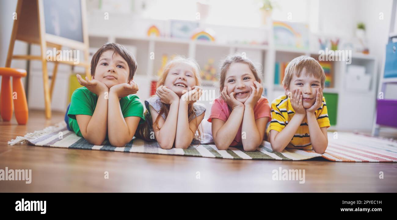 Group of children lying on the floor and looking in the camera. Stock Photo