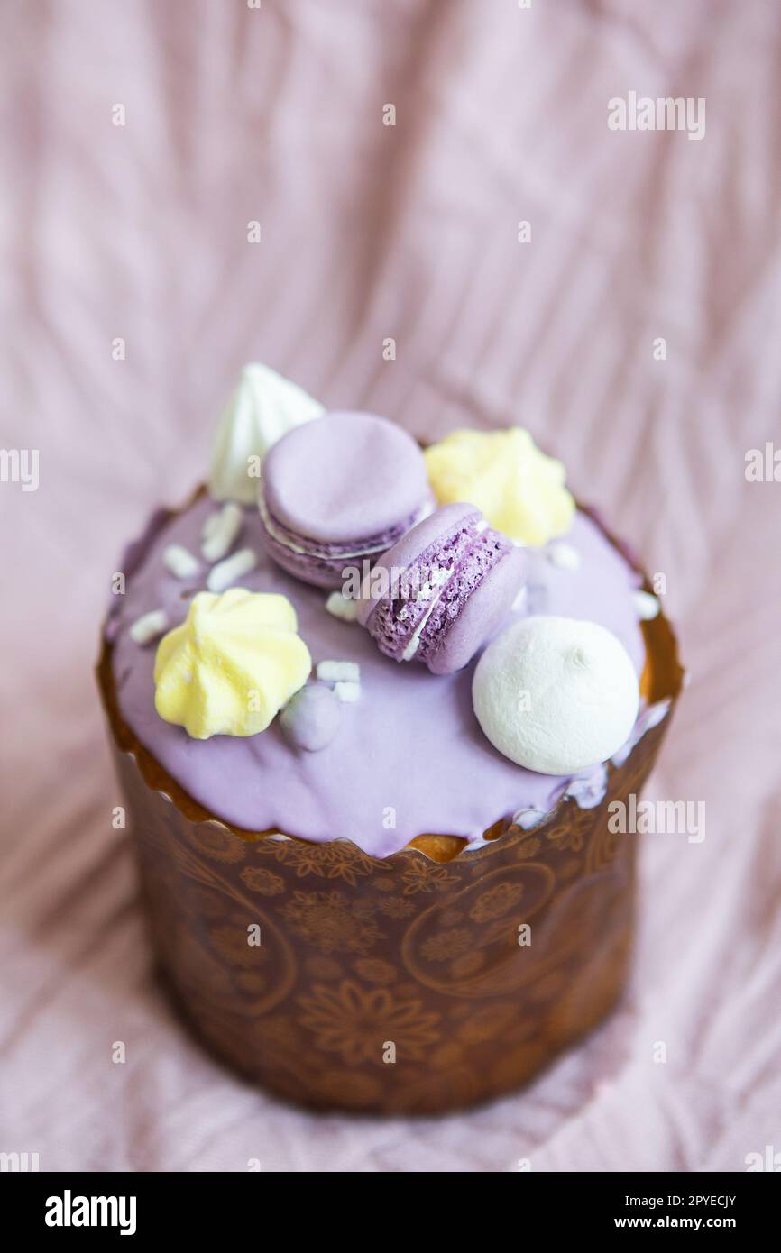 A traditional paska decorated with white Swiss chocolate and meringue stands on a lavender tablecloth. Easter holiday. Stock Photo