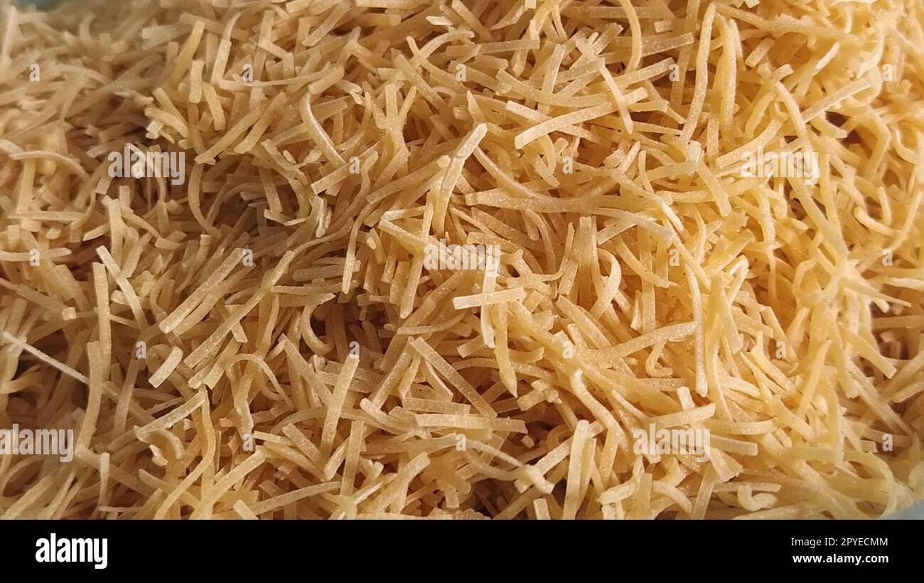 Thin dry vermicelli. Wheat flour product containing gluten, vitamins, carbohydrates, proteins and fats. Small pasta close-up. Fast food. Stock Photo