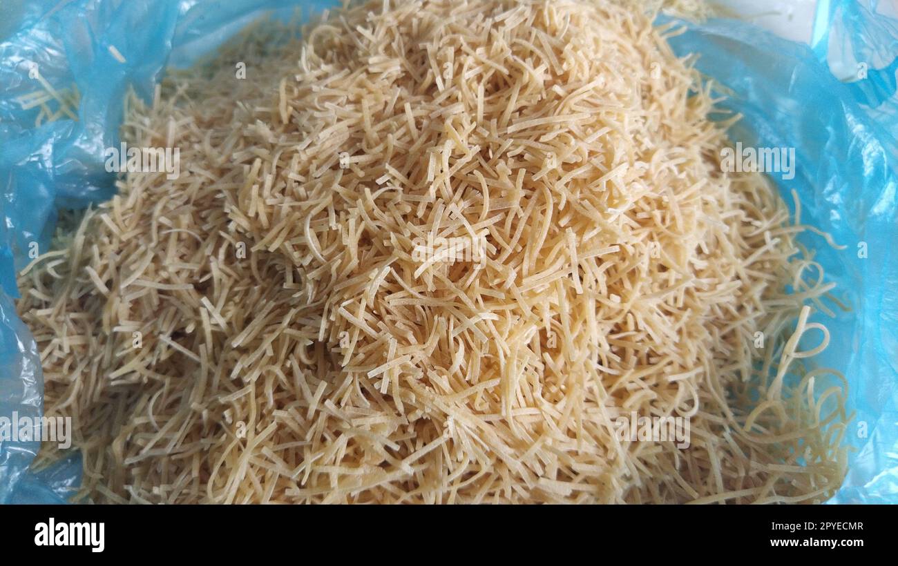 Thin dry vermicelli. Wheat flour product containing gluten, vitamins, carbohydrates, proteins and fats. Small pasta in a blue plastic bag. Fast food Stock Photo