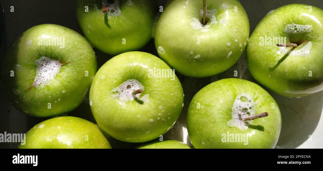 Wet soapy green apples. Thoroughly wash vegetables and fruits with water and soap. Prevention of infectious diseases. Apples closeup. Vegetarianism. Soapy foam sparkles in sunlight Stock Photo
