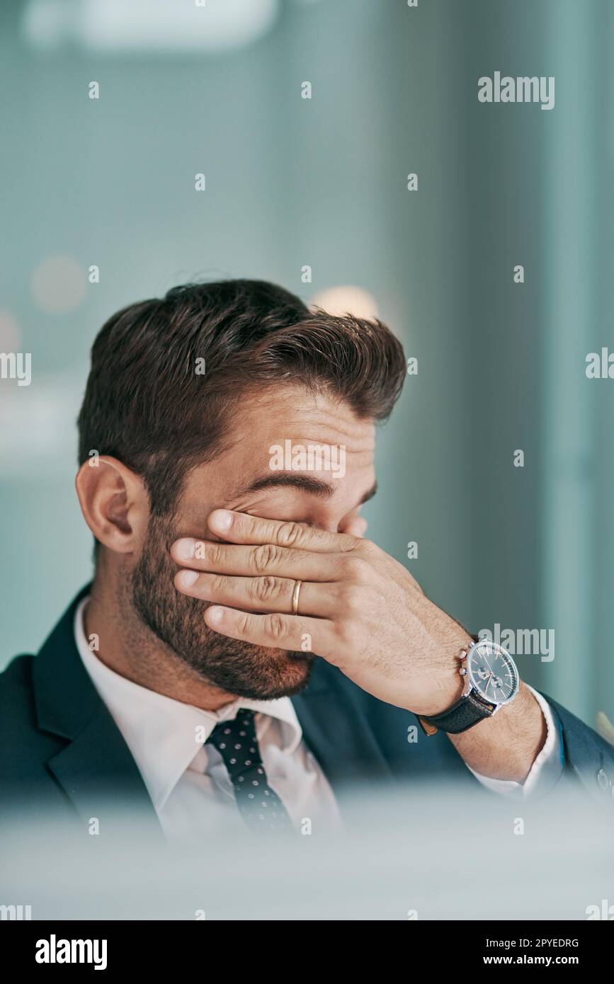 Its been one long day. a tired young businessman holding his eyes closed while being seated in the office. Stock Photo