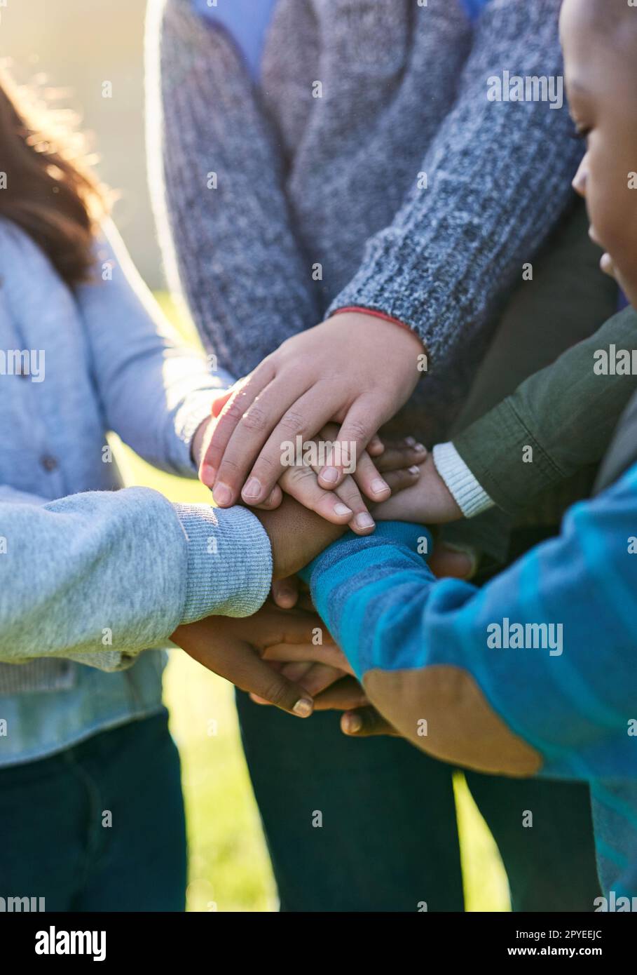 Uniting young minds. a group of unrecognizable elementary school kids joining their hands together in a huddle outside. Stock Photo