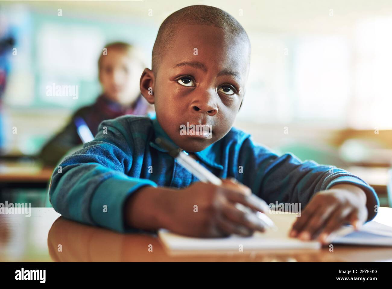 Hes such a hard worker in class. an adorable elementary school boy working in class. Stock Photo