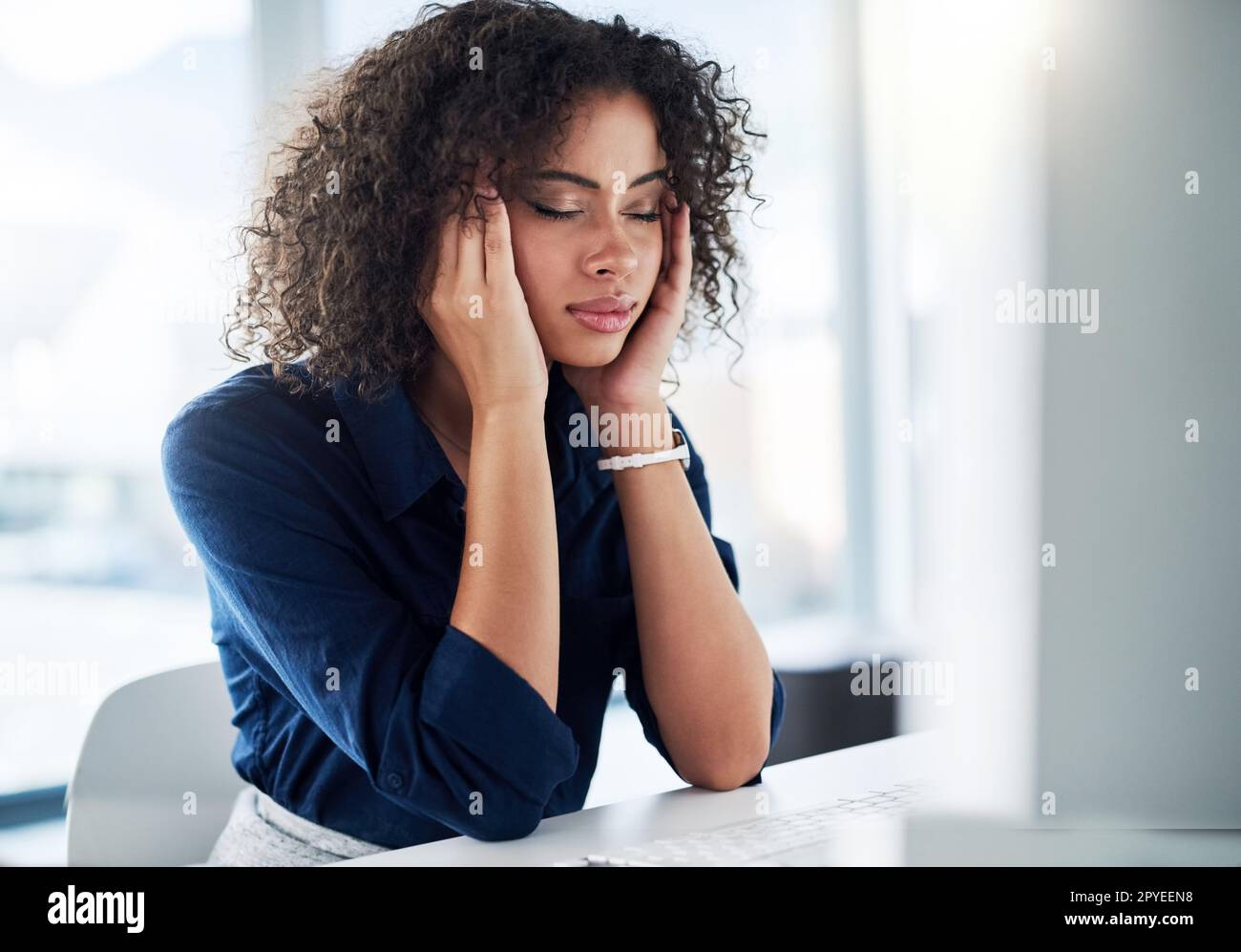 Headaches are a sure fire way to stop productivity. an attractive young businesswoman looking stressed while working at her desk in the office. Stock Photo