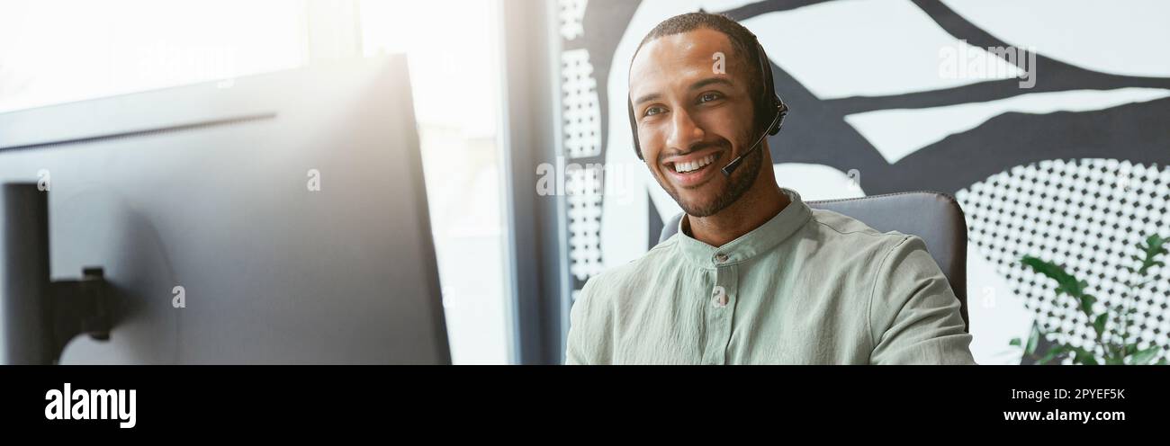 Smiling african businessman working on computer and making notes while sitting in modern office Stock Photo