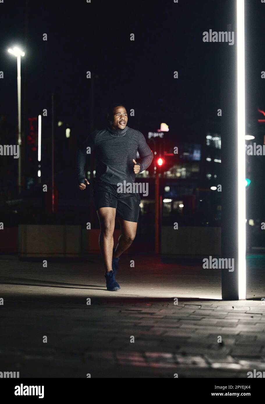 Running, fitness and man in night city for training muscle, body goals and lose weight challenge in motivation, energy and speed. Sports, athlete and cardio runner in the dark or urban street lights Stock Photo