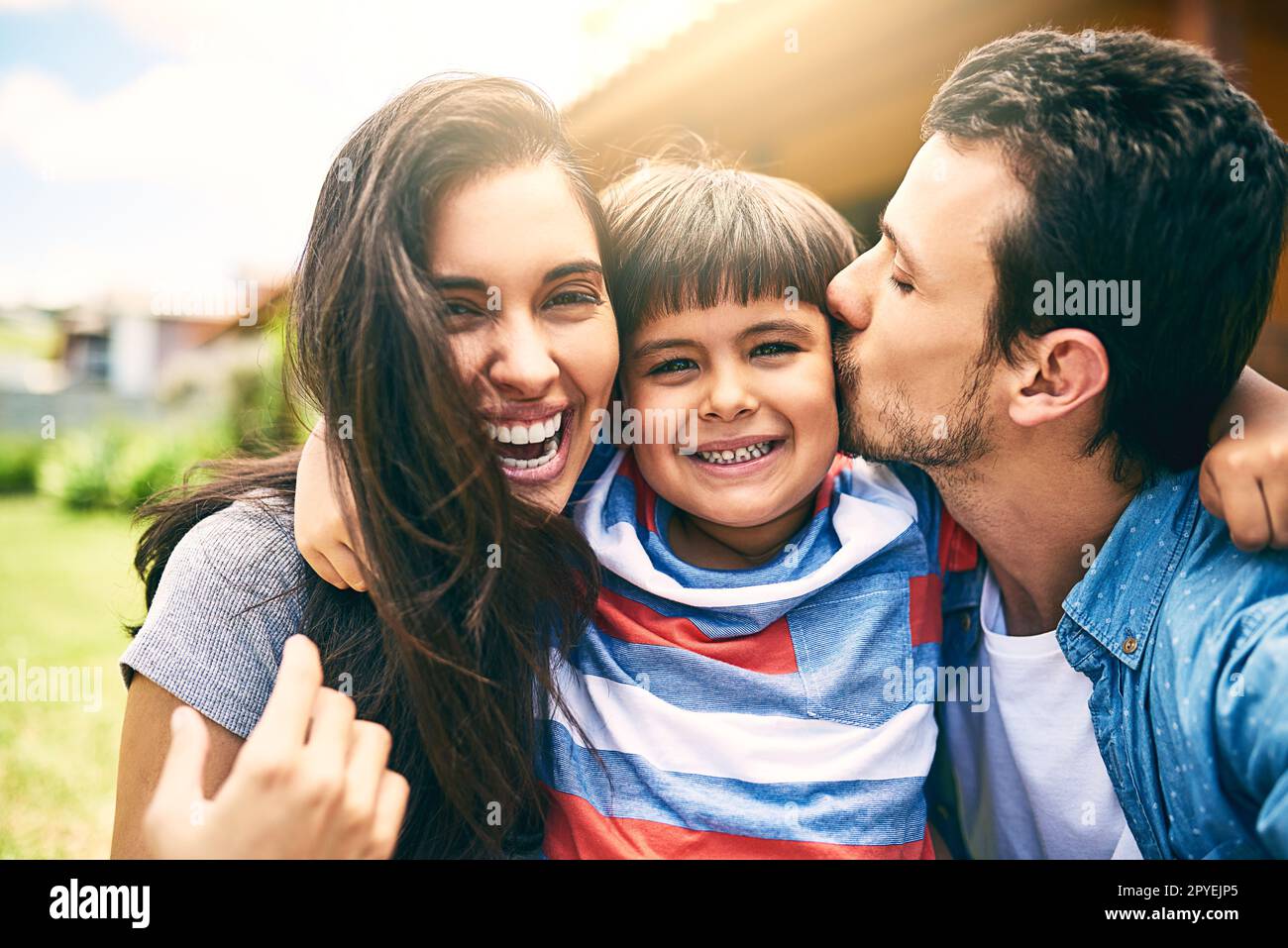 Hes such a joy. Cropped portrait of a happy young family of three sitting outside in their backyard. Stock Photo