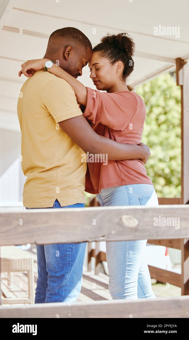 Black couple, love and hug while outdoor on patio at. home while together for trust, support and care in a healthy marriage. Man and woman with gratitude, commitment and happiness while on holiday Stock Photo