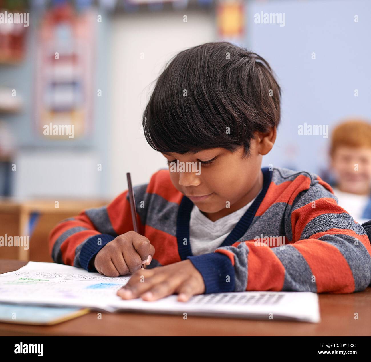 He loves writing. elementary school children in class. Stock Photo