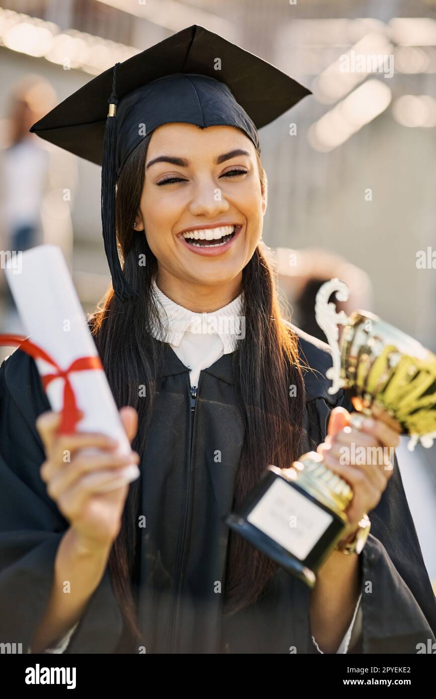 I feel like a true champion. Portrait of a student holding her diploma and trophy on graduation