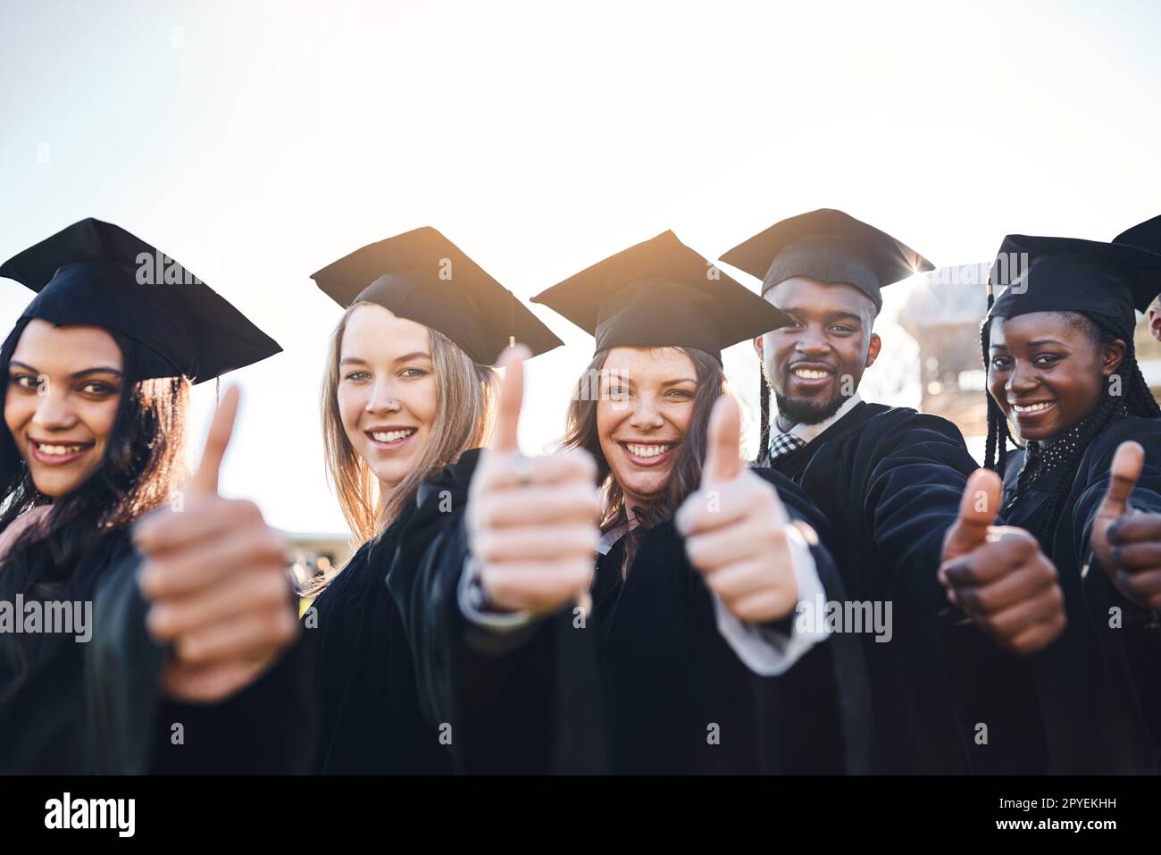 1. Your time as a caterpillar has expired. Your wings are ready.Portrait of a group of students showing thumbs up on graduation day. Stock Photo