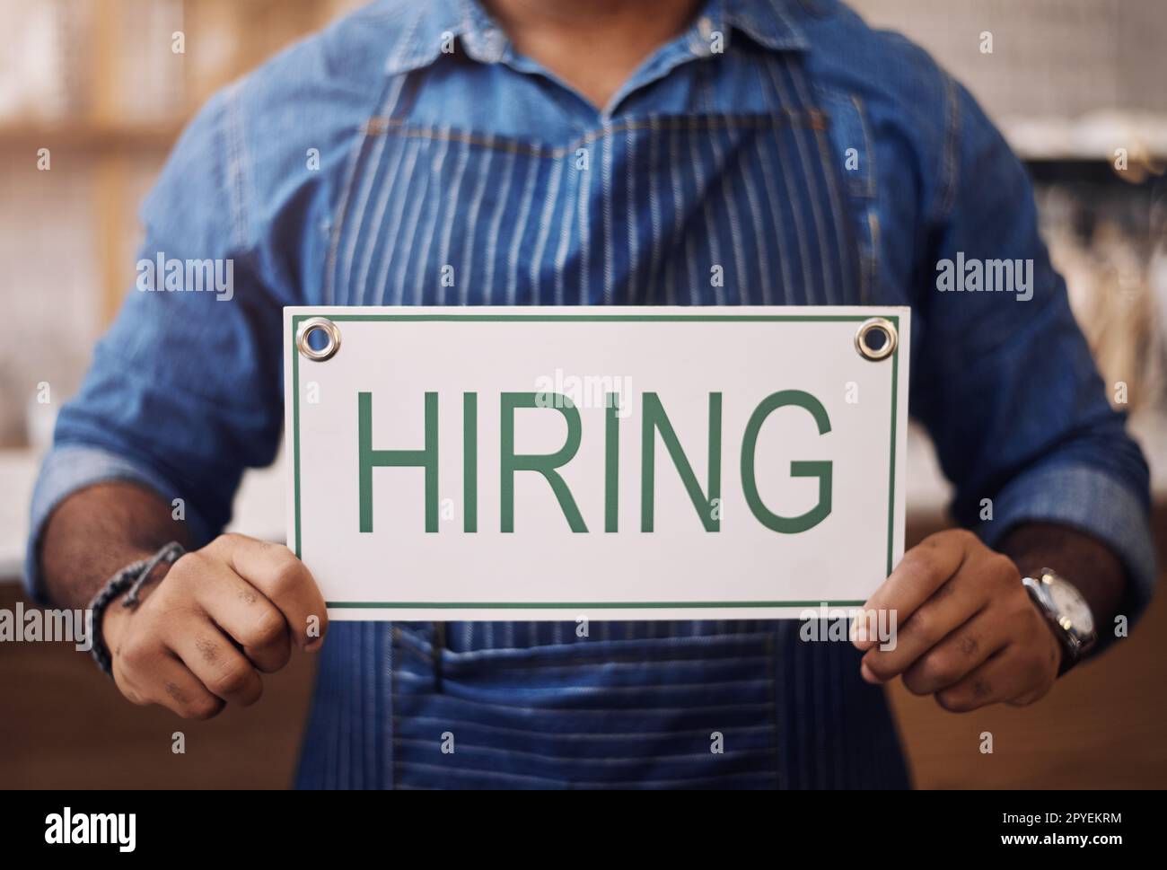 We have some job opportunities available. Closeup shot of an unrecognisable man holding up a hiring sign in his store. Stock Photo
