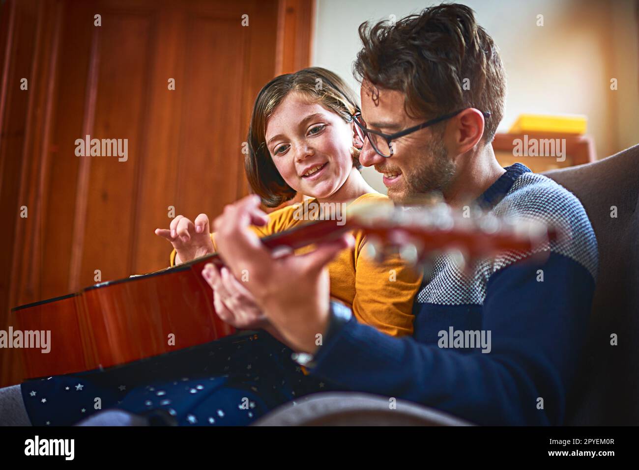 Learning to be as great as her dad. a little girl playing the guitar with her father at home. Stock Photo