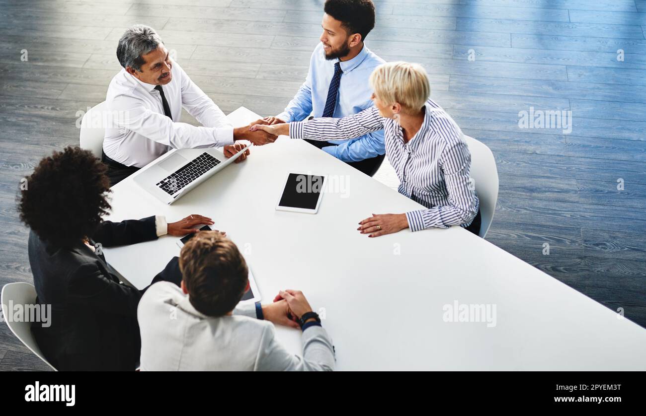 Im glad weve reached an agreement. businesspeople shaking hands during a meeting in an office. Stock Photo
