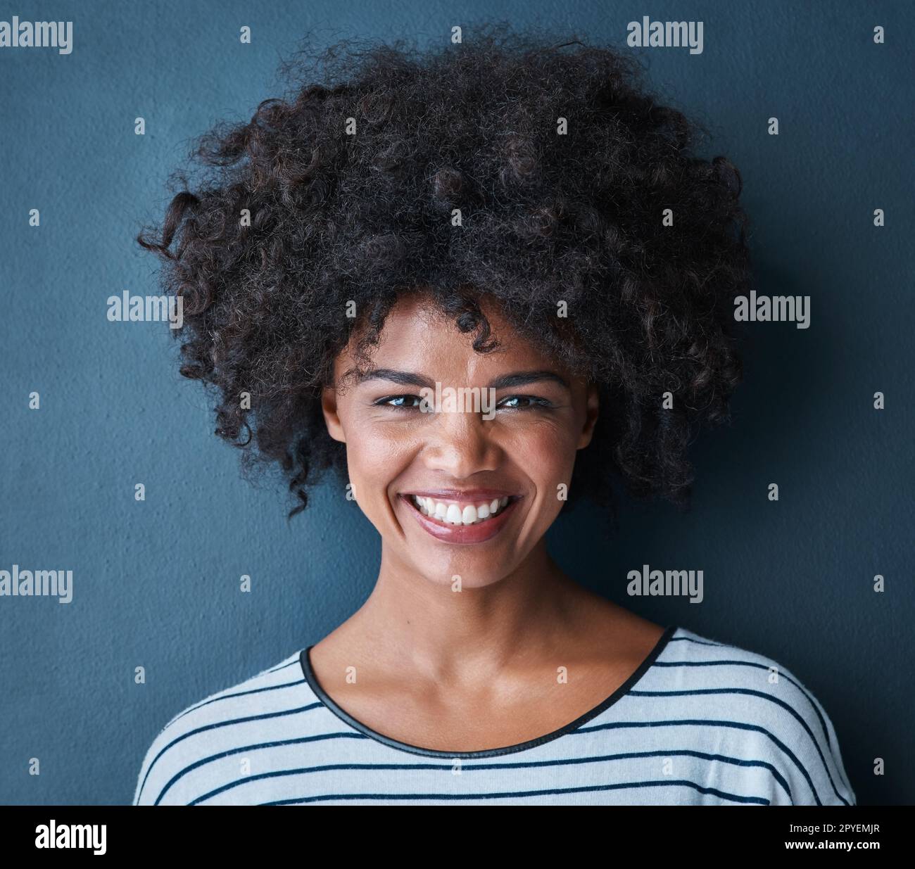 Making life beautiful one smile at a time. Studio portrait of an attractive and happy young woman posing against a blue background. Stock Photo