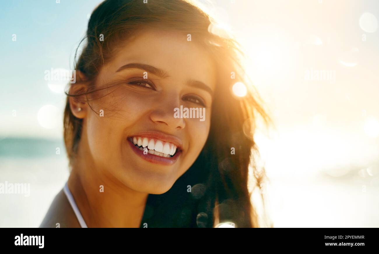 The simple act of smiling communicates self-confidence and friendliness. Closeup shot of a beautiful young woman spending some time at the beach. Stock Photo