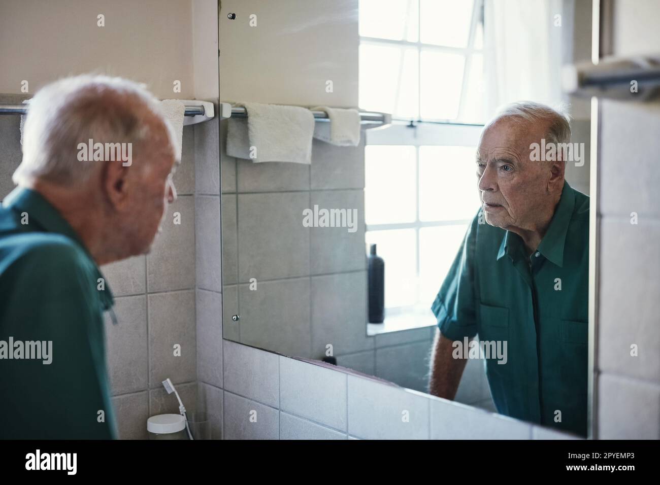 How did I get so old. a senior man looking in his bathroom mirror. Stock Photo