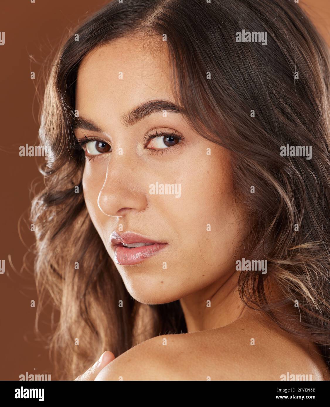 Woman, face skincare or curly hairstyle on brown studio background in color dye advertising, self love or Brazilian keratin treatment. Portrait, beauty model or brunette waves and natural makeup glow Stock Photo