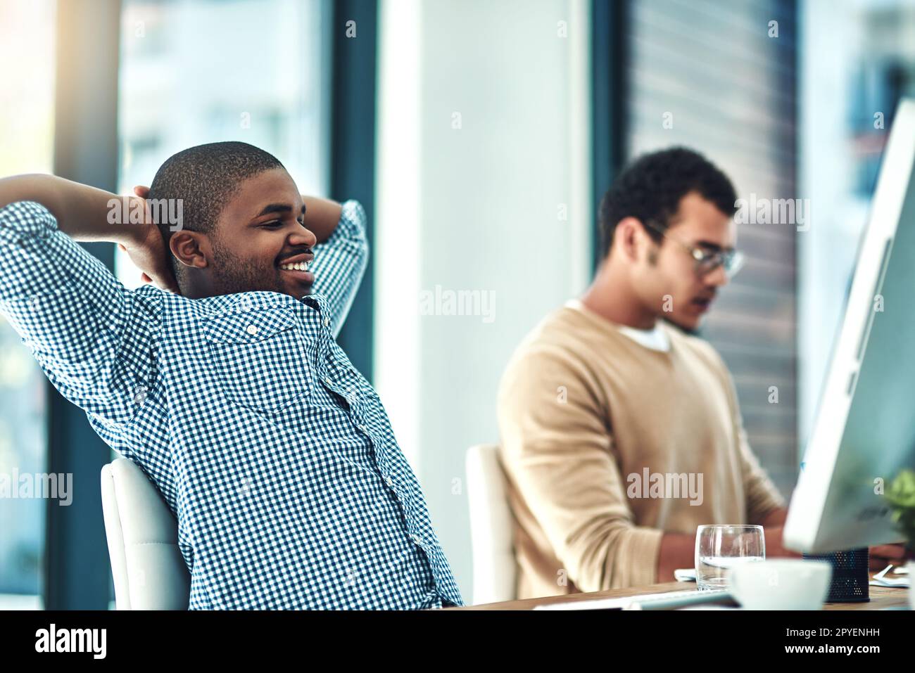 I sure do love my job. a young designer looking relaxed at his desk. Stock Photo