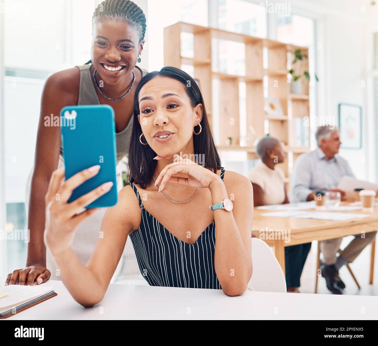 Selfie, friends and a business black woman posing for a photograph in the office with her colleague. Phone, diversity and social media with a female employee and coworker taking a picture at work Stock Photo