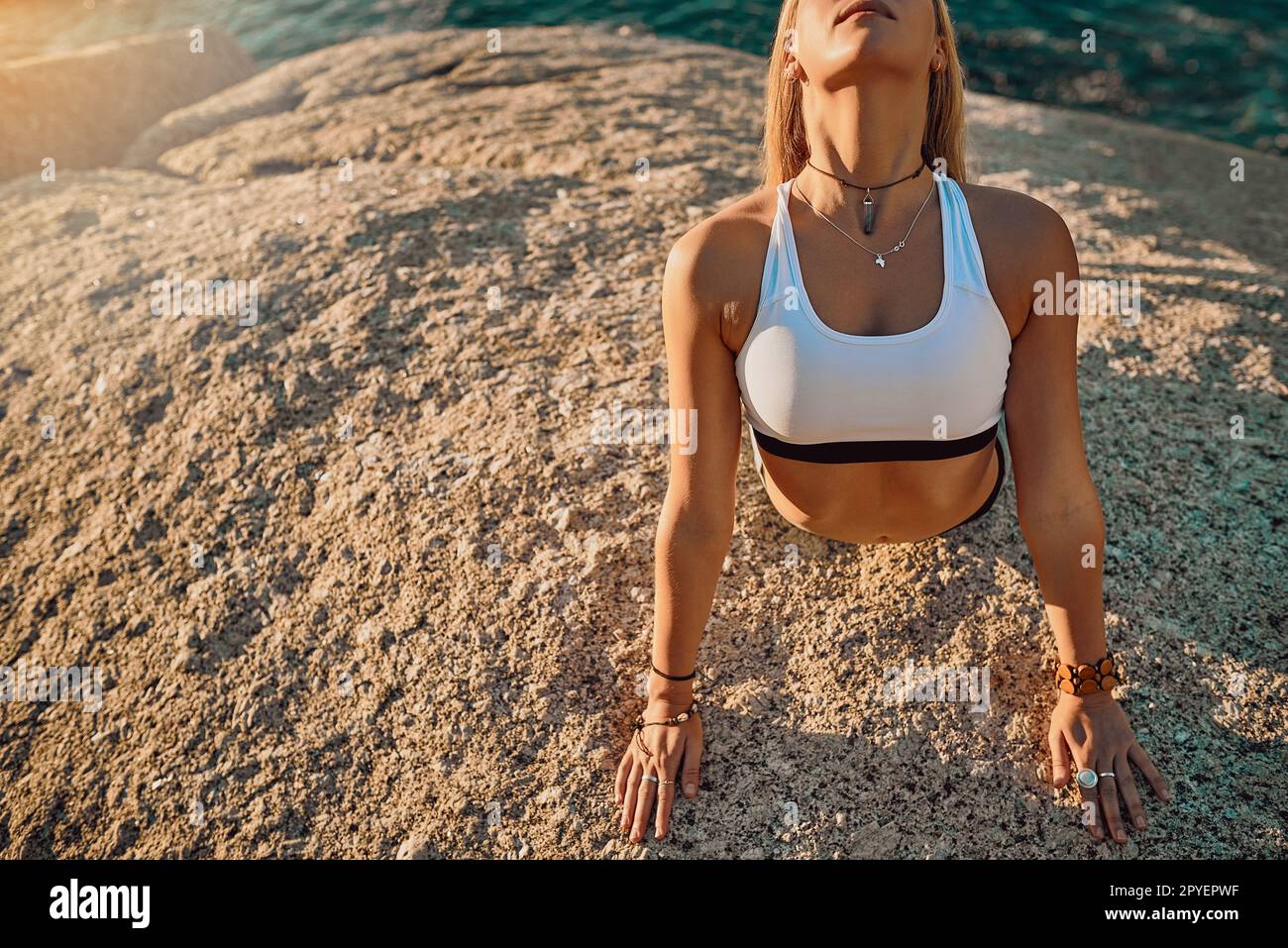 Drop and give me zen. an athletic young woman practicing yoga on the beach. Stock Photo