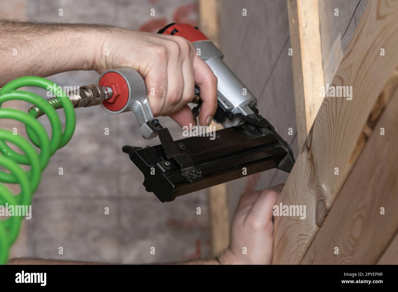 Unrecognizable cropped male hands using pneumatic nailer, nail gun with