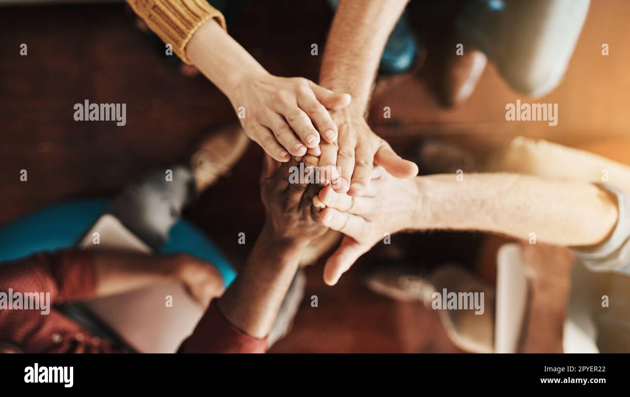 Uniting to reach their common goals. High angle shot of a group of unrecognizable businesspeople high fiving together. Stock Photo
