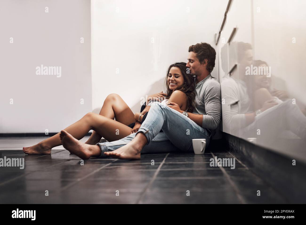 Romance turns a house into paradise. an affectionate young couple sitting on the kitchen floor. Stock Photo