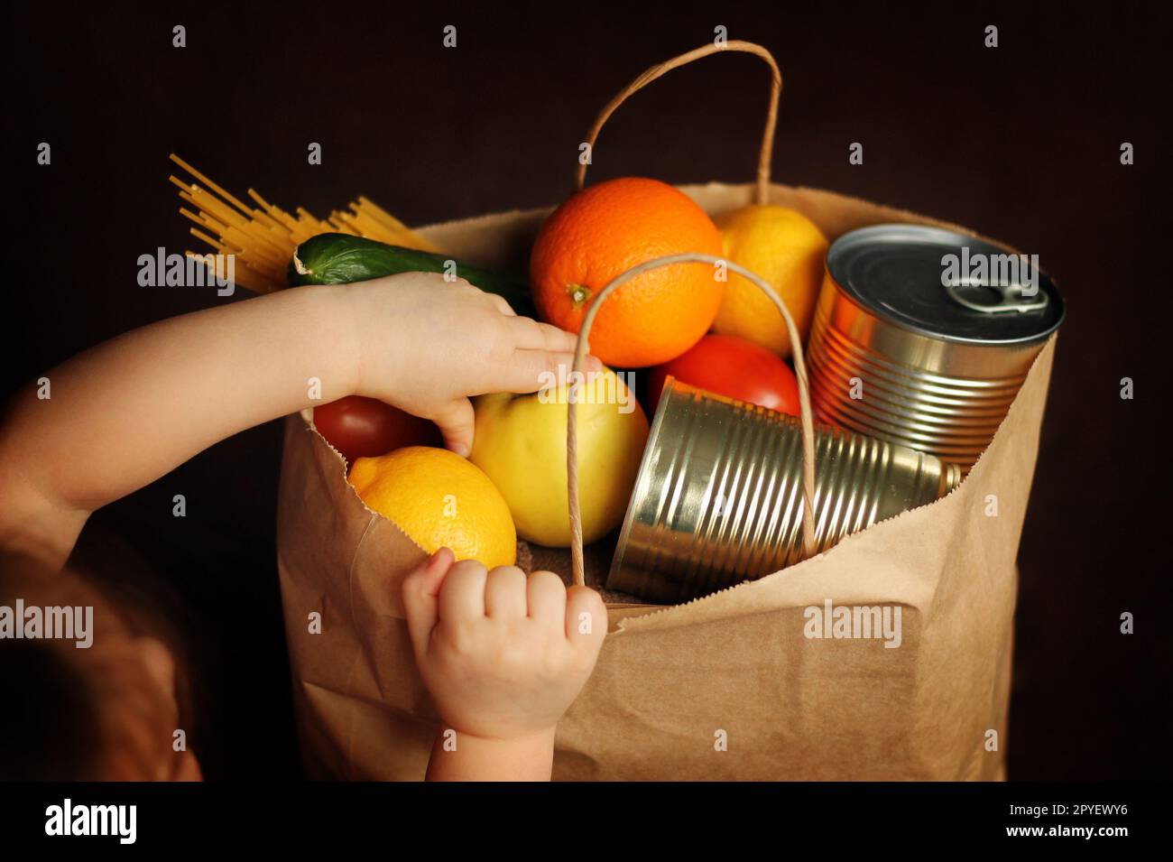 Little girl puts products in a paper bag on a brown background Stock