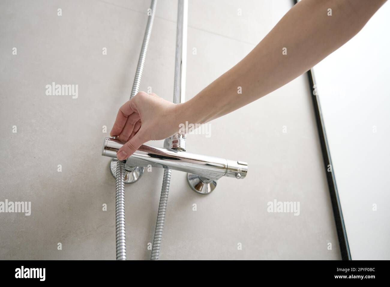Female hand turn on shower faucet. Modern shower set in bathroom