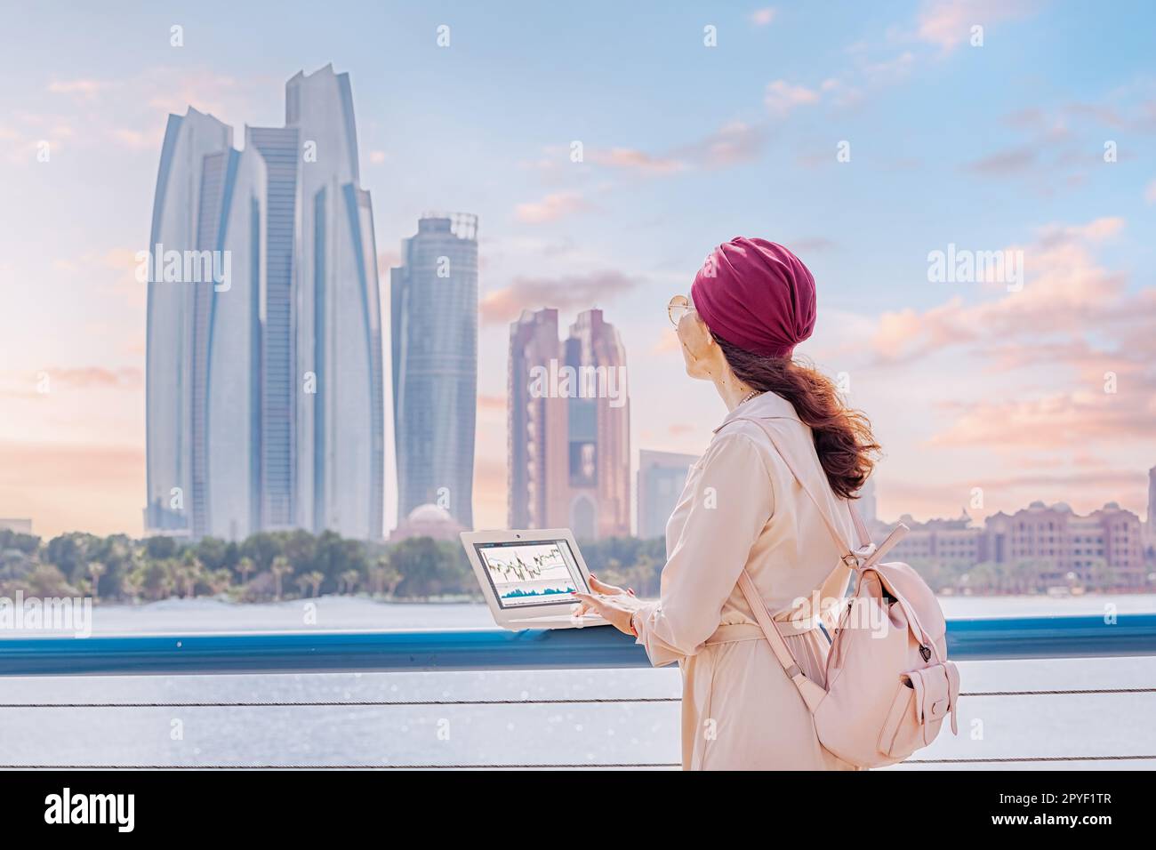 Asian girl working on laptop with stock market exchange online graph